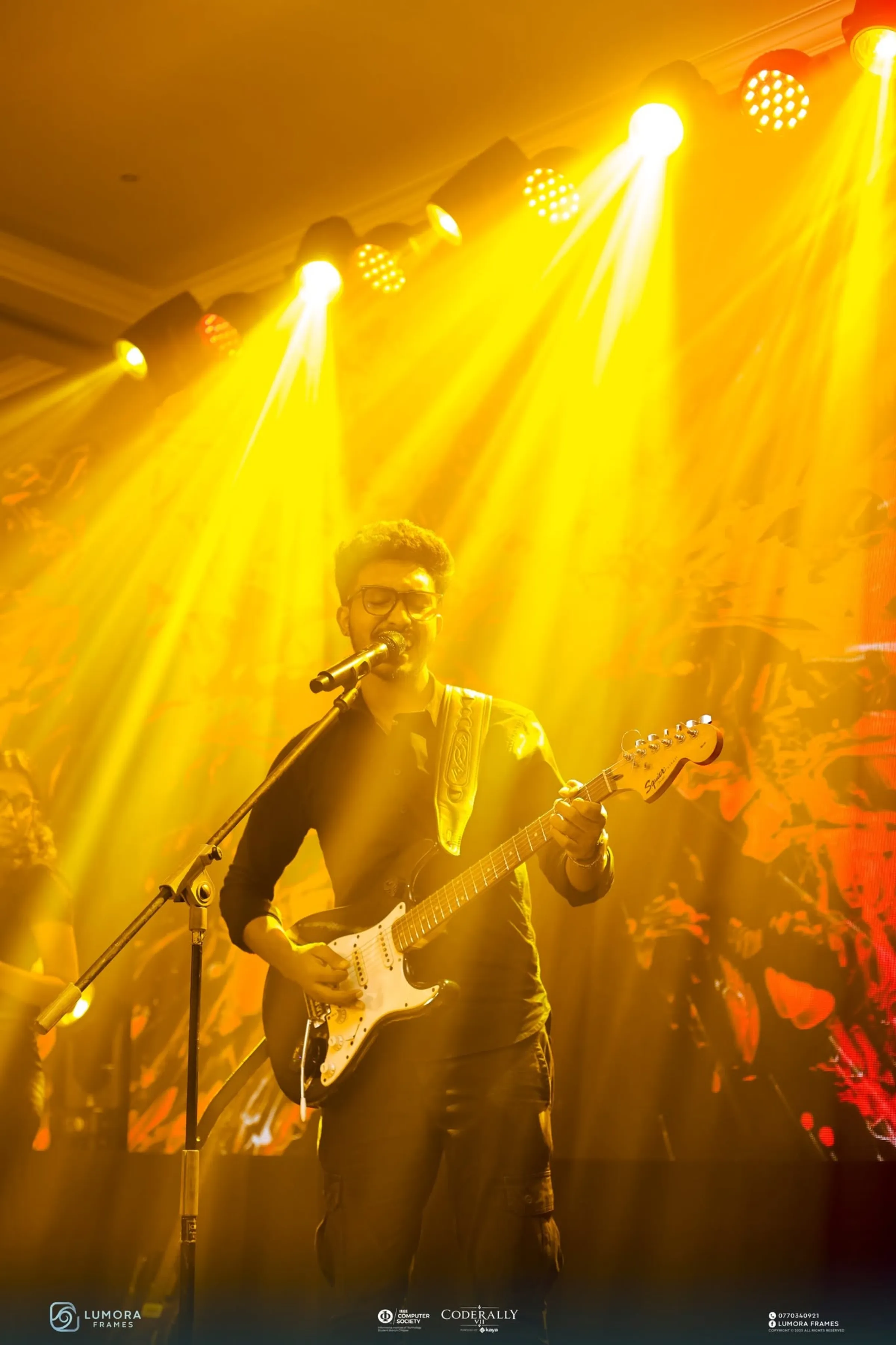 A guitarist performing in yellow stage lights